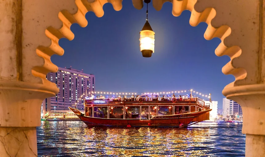 A beautiful view of the Dhow Cruise Dubai Creek, showcasing the traditional wooden boat sailing along Dubai Creek with the city skyline in the background.