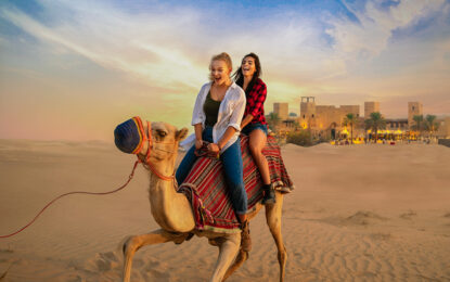 Tourists enjoying a desert safari with dune bashing and camel rides during a vibrant sunset in the heart of the Dubai Desert Safari.