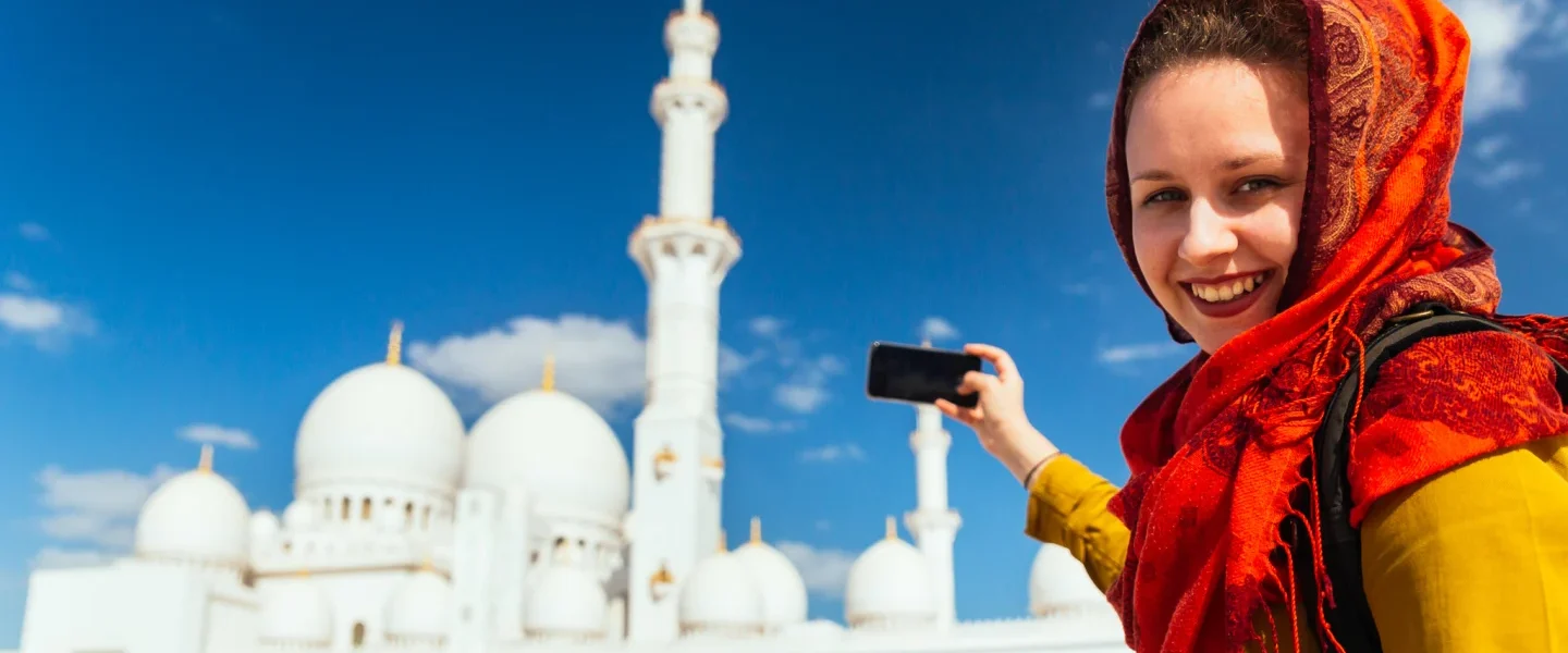 Scenic view of Abu Dhabi city tour with Ferrari World Yas Island, the Formula Rossa roller coaster, and the grand architecture of Sheikh Zayed Grand Mosque.