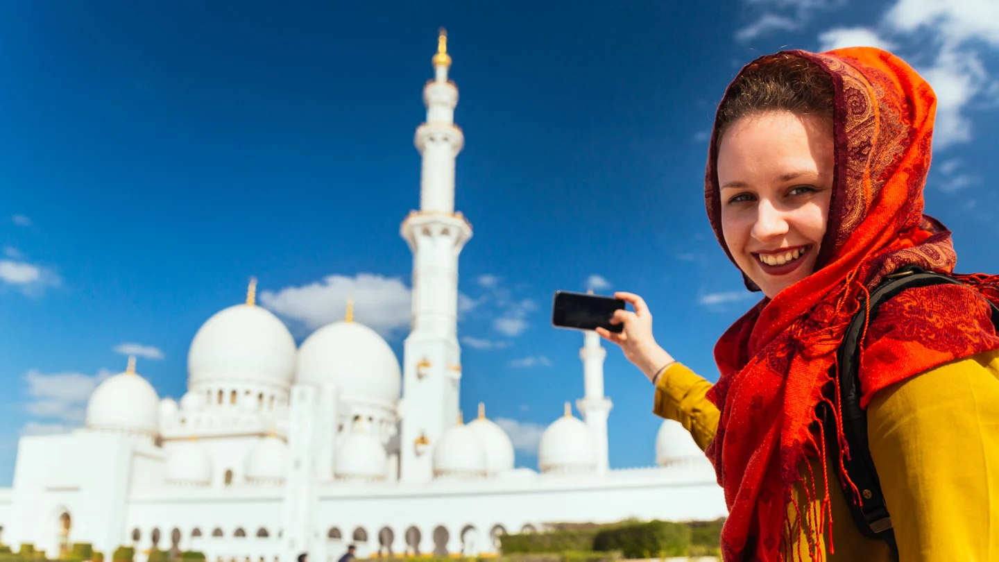 Scenic view of Abu Dhabi city tour with Ferrari World Yas Island, the Formula Rossa roller coaster, and the grand architecture of Sheikh Zayed Grand Mosque.