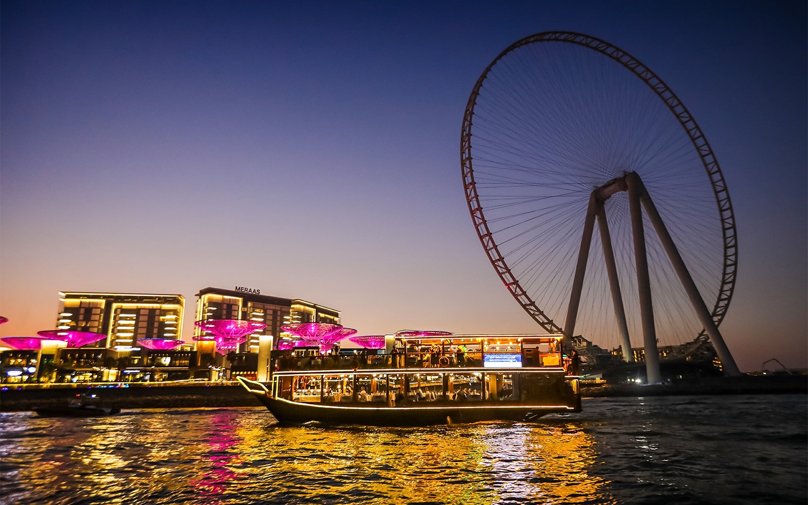Traditional dhow boat lit up at night during a Marina Dhow Cruise with Dinner at Dubai Marina, offering scenic views and fine dining.