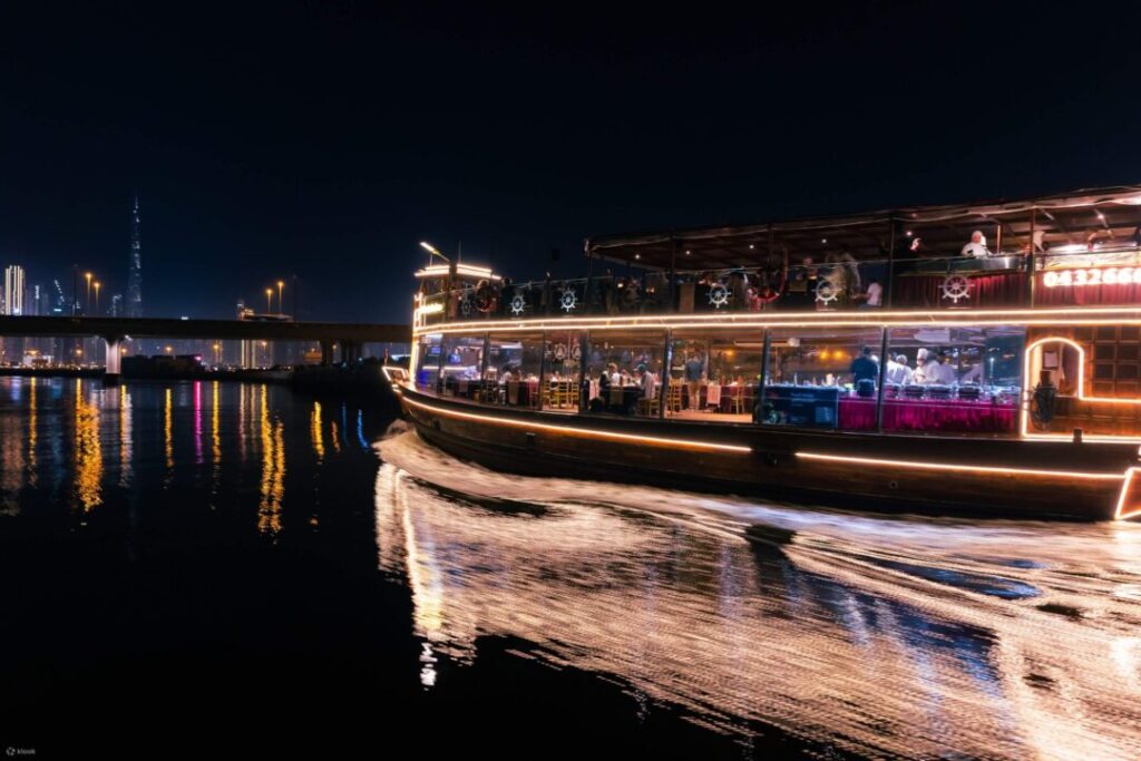 Dubai Canal Dhow Cruise With Dinner › Forever Tourism LLC A brightly lit cruise boat sails at night with its lights reflecting on the water. The scene highlights the peaceful Canal Bay Dinner Cruise Dubai experience. Guests can explore exciting Dubai Canal Dhow Cruise offers during the season. Many visitors enjoy the smooth Dubai Water Canal Dhow Cruise for relaxation. The elegant VIP Dhow Cruise Dubai Canal provides a luxurious evening on the water. Guests also enjoy dining on the Dubai Canal Dhow Cruise with Dinner. Beautiful views appear in many VIP Dhow Cruise Dubai Canal photos online.