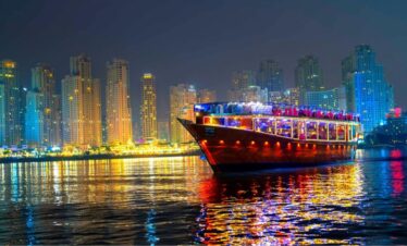 brightly lit cruise boat sails at night with its lights reflecting on the water. This scene highlights the charm of the canal dhow cruise Dubai, offering peaceful moments. Guests enjoy elegant dining on the canal dinner cruise Dubai. Many visitors love the comfort of the luxury canal dinner cruise Dubai. You can also choose the relaxing canal bay dinner cruise Dubai. Travelers often explore exciting Dubai canal dhow cruise offers. The experience remains popular on the Dubai Water Canal Dhow Cruise. Many guests enjoy the Dubai canal dhow cruise with dinner for beautiful views.