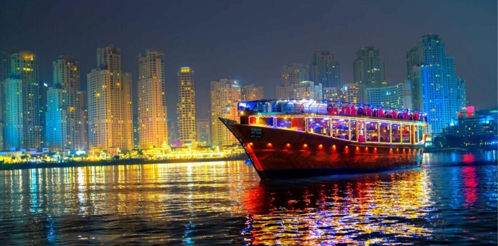 brightly lit cruise boat sails at night with its lights reflecting on the water. This scene highlights the charm of the canal dhow cruise Dubai, offering peaceful moments. Guests enjoy elegant dining on the canal dinner cruise Dubai. Many visitors love the comfort of the luxury canal dinner cruise Dubai. You can also choose the relaxing canal bay dinner cruise Dubai. Travelers often explore exciting Dubai canal dhow cruise offers. The experience remains popular on the Dubai Water Canal Dhow Cruise. Many guests enjoy the Dubai canal dhow cruise with dinner for beautiful views.