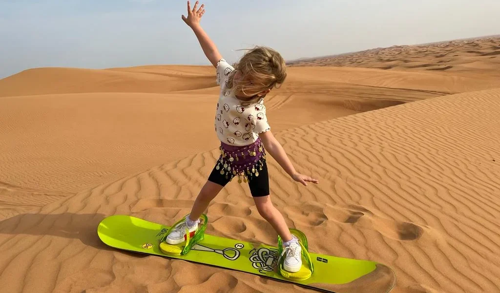Tourists enjoying a morning desert safari in Dubai with dune bashing and camel rides in the vast desert landscape.