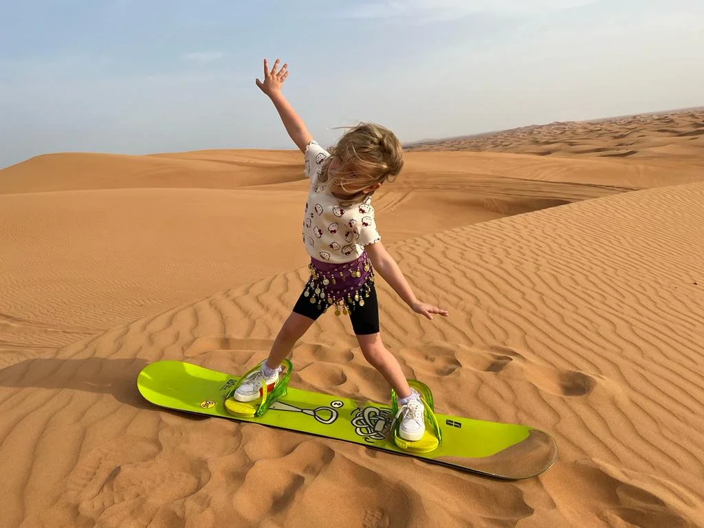 Tourists enjoying a morning desert safari in Dubai with dune bashing and camel rides in the vast desert landscape.