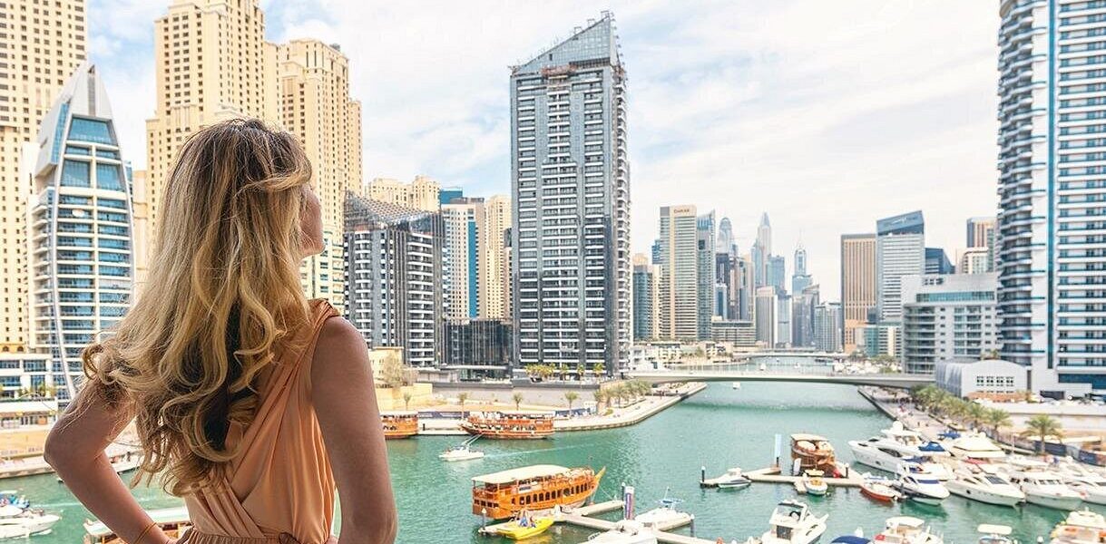 Tourists enjoying a Dubai city tour with City Sightseeing Dubai bus, Desert Safari adventure, and Burj Khalifa in the background.