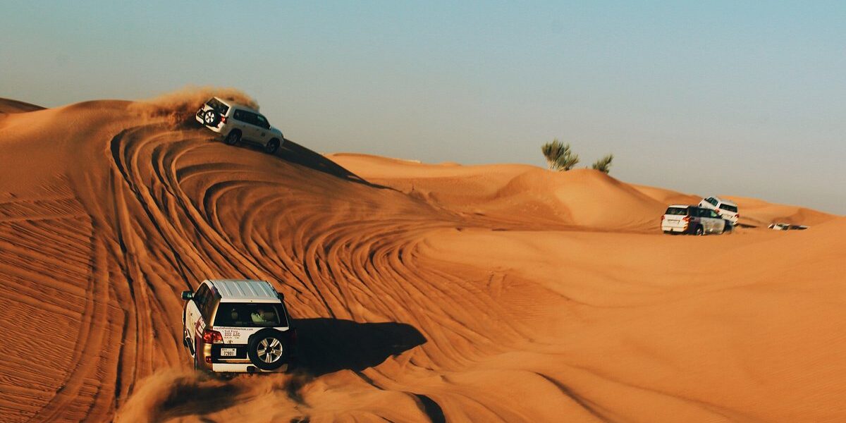 Tourists enjoying a Dubai Desert Safari with dune bashing, camel rides, and scenic views of the vast Dubai desert during sunset.