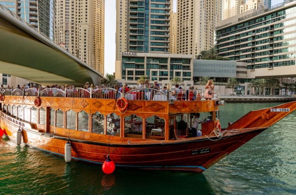 Traditional Dhow boat cruising through Dubai Marina at night, offering a scenic Marina Dhow Cruise with Dinner and views of illuminated skyscrapers.
