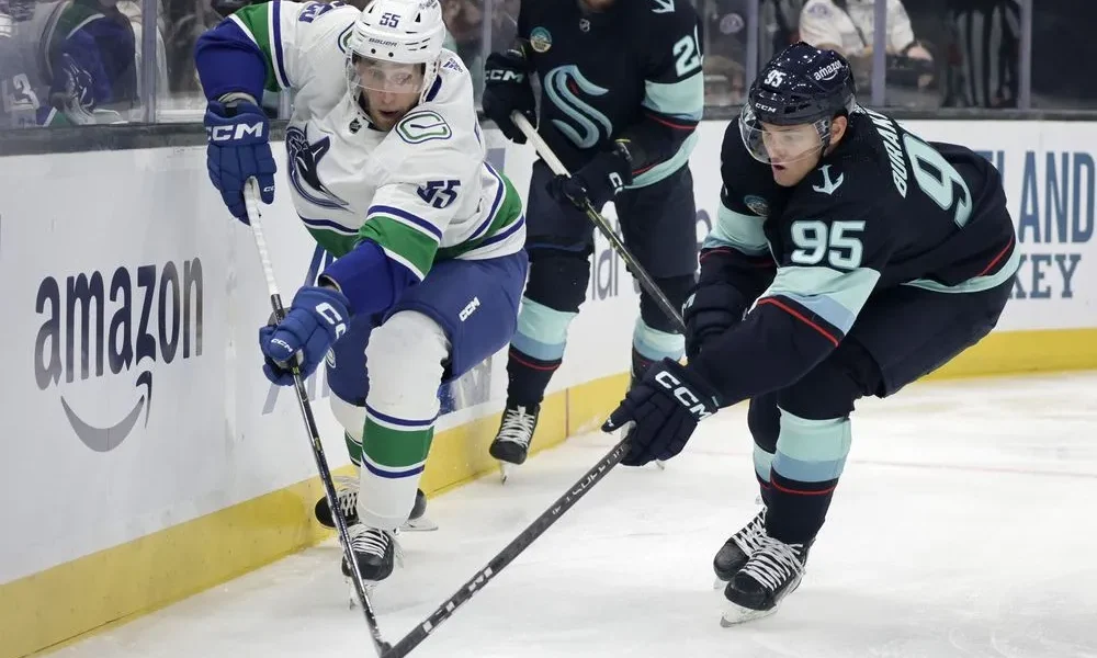 Intense on-ice action during the Kraken vs Canucks game featuring players from Seattle Kraken and Canucks competing for the puck.