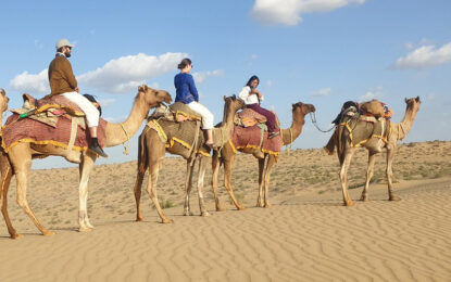 Tourists enjoying a desert safari Dubai experience with dune buggy and quad biking in the golden sand dunes.