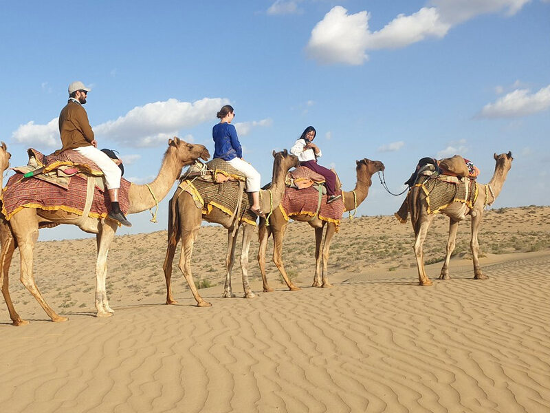 Tourists enjoying a desert safari Dubai experience with dune buggy and quad biking in the golden sand dunes.