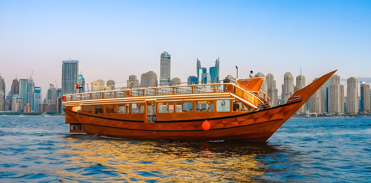 Scenic view of a traditional dhow boat offering a Dhow Cruise in Dubai with dinner and illuminated city skyline in the background.