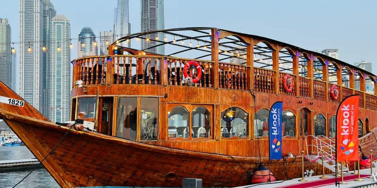 Traditional dhow boat sailing on Dubai Marina at night during a marina dhow cruise with dinner, showcasing city lights and waterfront skyline.