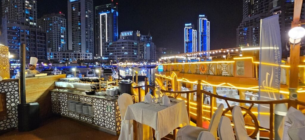 Dubai Creek Dhow Cruise: 500+ Reviews Say Wow! › Forever Tourism LLC Traditional wooden boat on a Dubai Creek Dhow Cruise with guests enjoying a Dhow Dinner Cruise along the Dhow Cruise Creek at sunset.