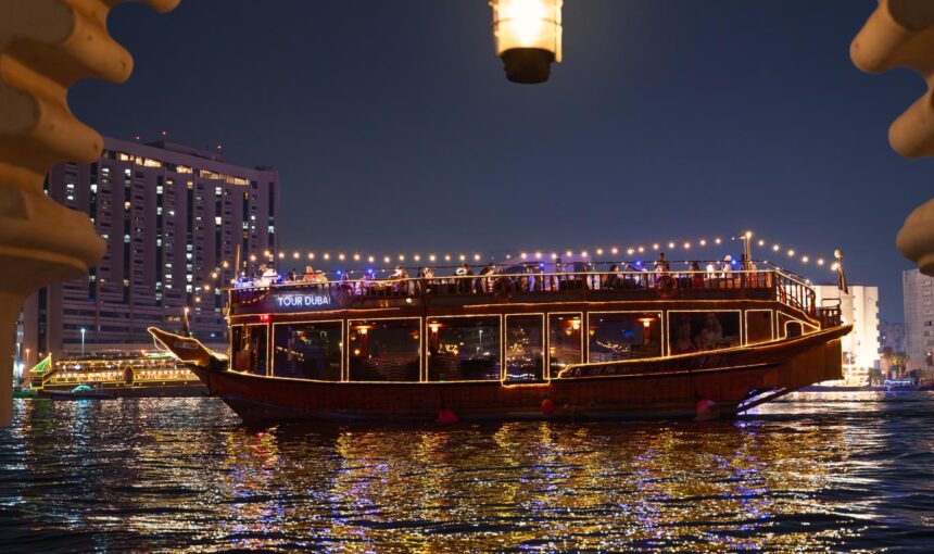 Dubai Creek Dhow Cruise: 500+ Reviews Say Wow! › Forever Tourism LLC Traditional wooden boat on a Dubai Creek Dhow Cruise with guests enjoying a Dhow Dinner Cruise along the Dhow Cruise Creek at sunset.