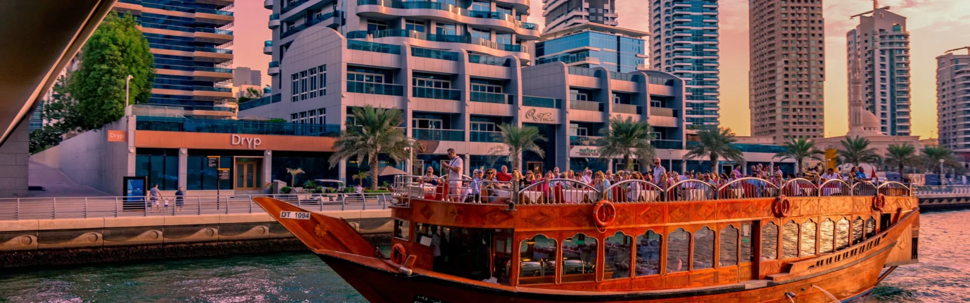 Traditional dhow boat sailing through Dubai Marina at sunset during a Marina Dhow Cruise with Dinner.