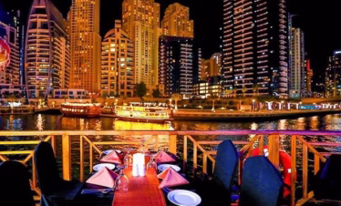 Traditional dhow boat sailing in Dubai Marina during a sunset marina dhow cruise with dinner, with guests enjoying a buffet and scenic views.
