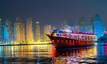 Guests dining aboard a traditional dhow during a scenic dhow marina cruise with dinner, part of an elegant dhow cruise tour experience.