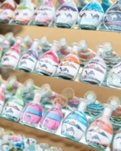 Colorful sand art bottles with desert and camel designs, a popular souvenir from Desert Safari Dubai.
