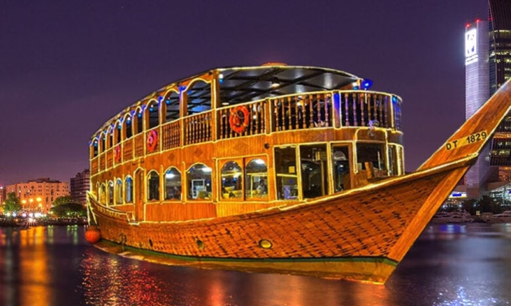 Traditional dhow boat sailing on Dubai Creek at sunset during a creek dhow cruise, offering scenic views and a luxurious cruise dinner Dubai experience.