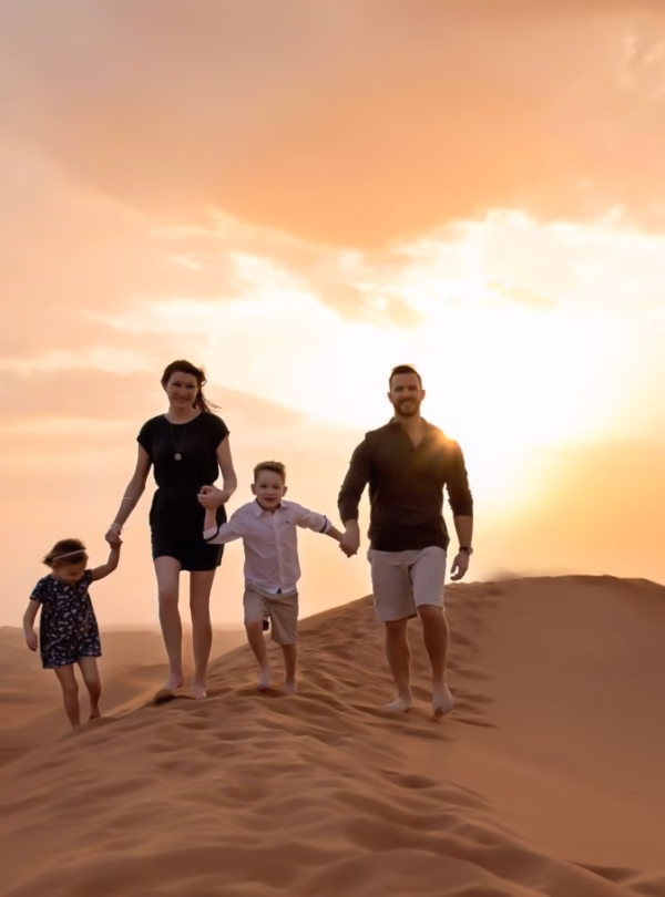 Family enjoying Dubai desert safari with camel ride, dune bashing, and quad biking in the golden desert dunes.