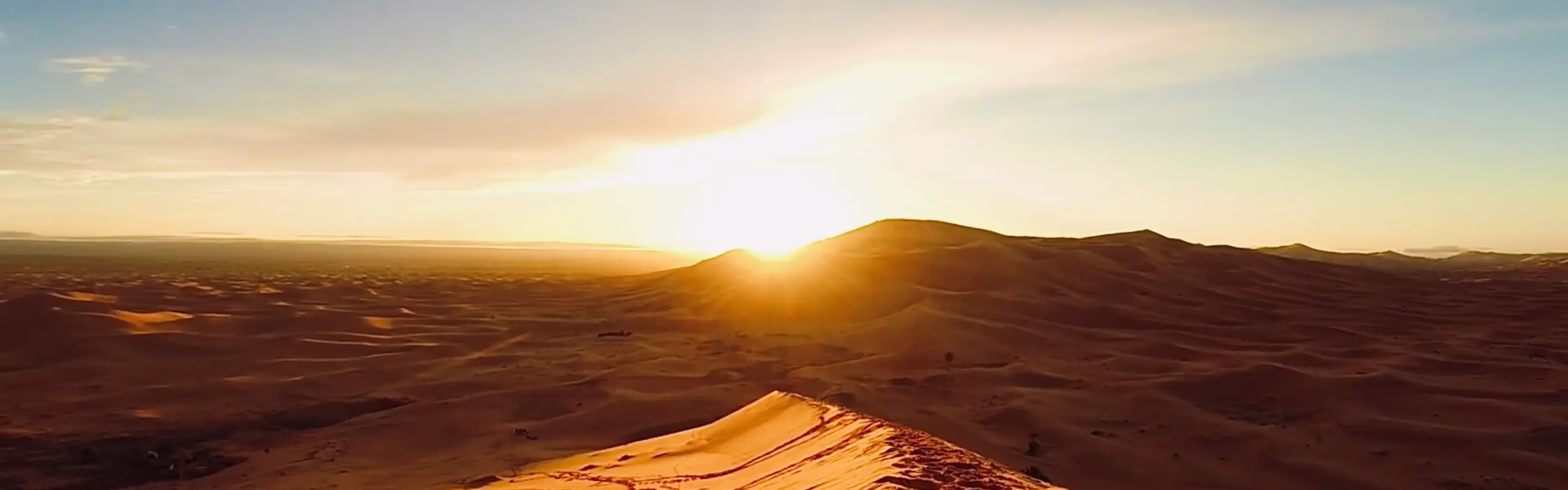 Tourists enjoying Dubai morning desert safari with quad biking, dune bashing, camel rides, and a stunning sunrise over the desert.