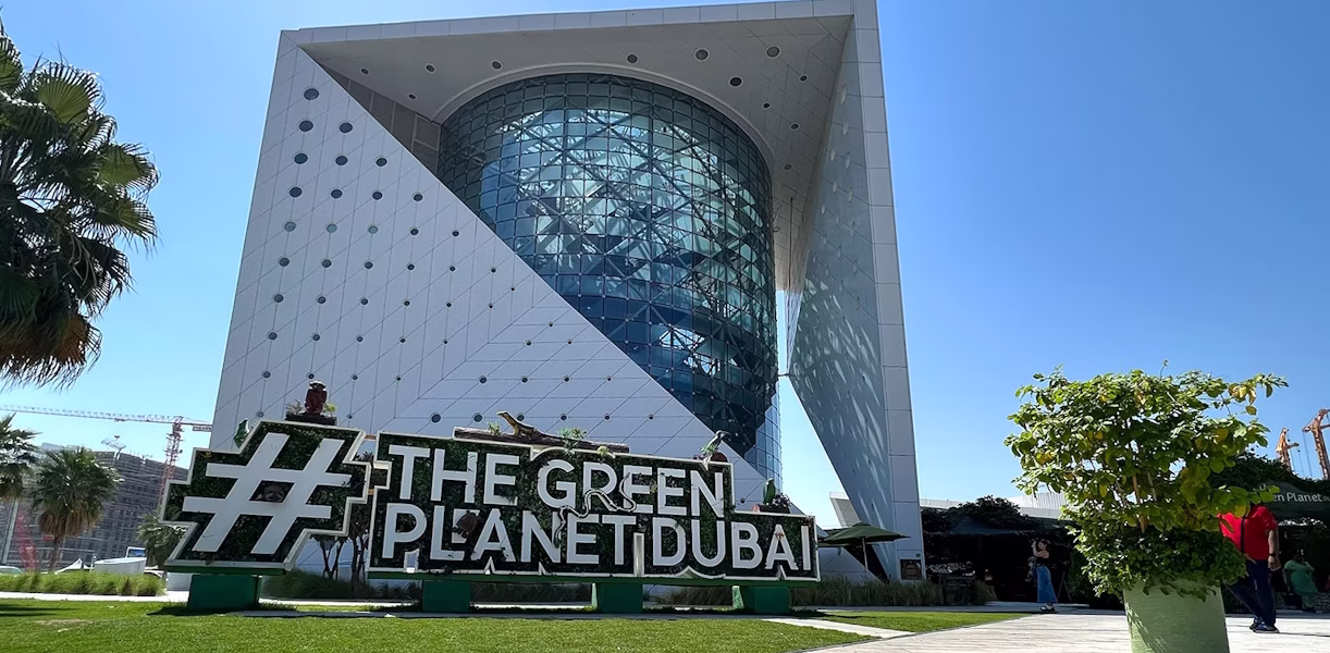 The Green Planet Dubai rainforest exhibit showing lush greenery and exotic animals – includes visitor info on timings, location, and ticket prices.