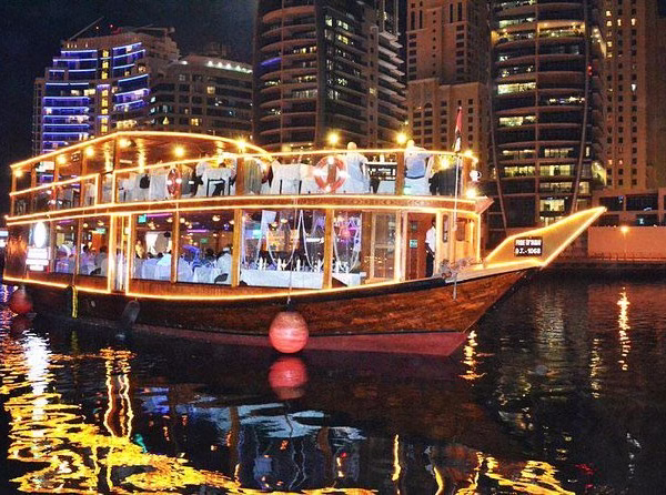 Traditional wooden boat set for a creek dhow dinner cruise on Dubai's serene dhow creek with guests enjoying a scenic dhow cruise dinner tour.