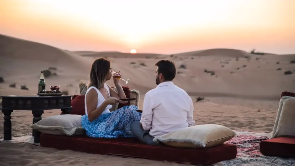 Tourists enjoying desert safari Dubai dune bashing in a 4x4 vehicle amid golden sand dunes with a scenic desert backdrop.