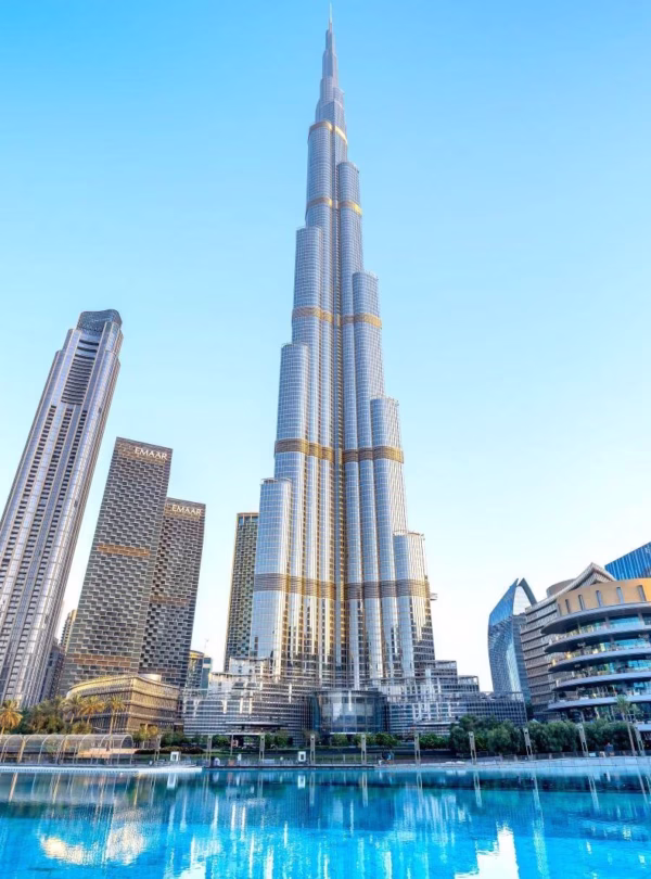 Red Dubai city tour bus with tourists enjoying a hop-on hop-off sightseeing experience in front of iconic Dubai landmarks.