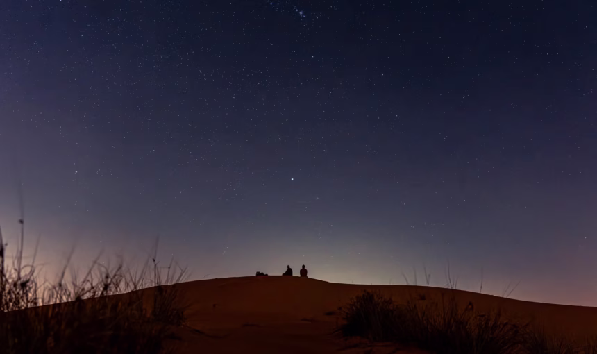 Tourists enjoying a night desert safari Dubai with sand dune bashing, camel trip, and BBQ dinner in the scenic Dubai desert.