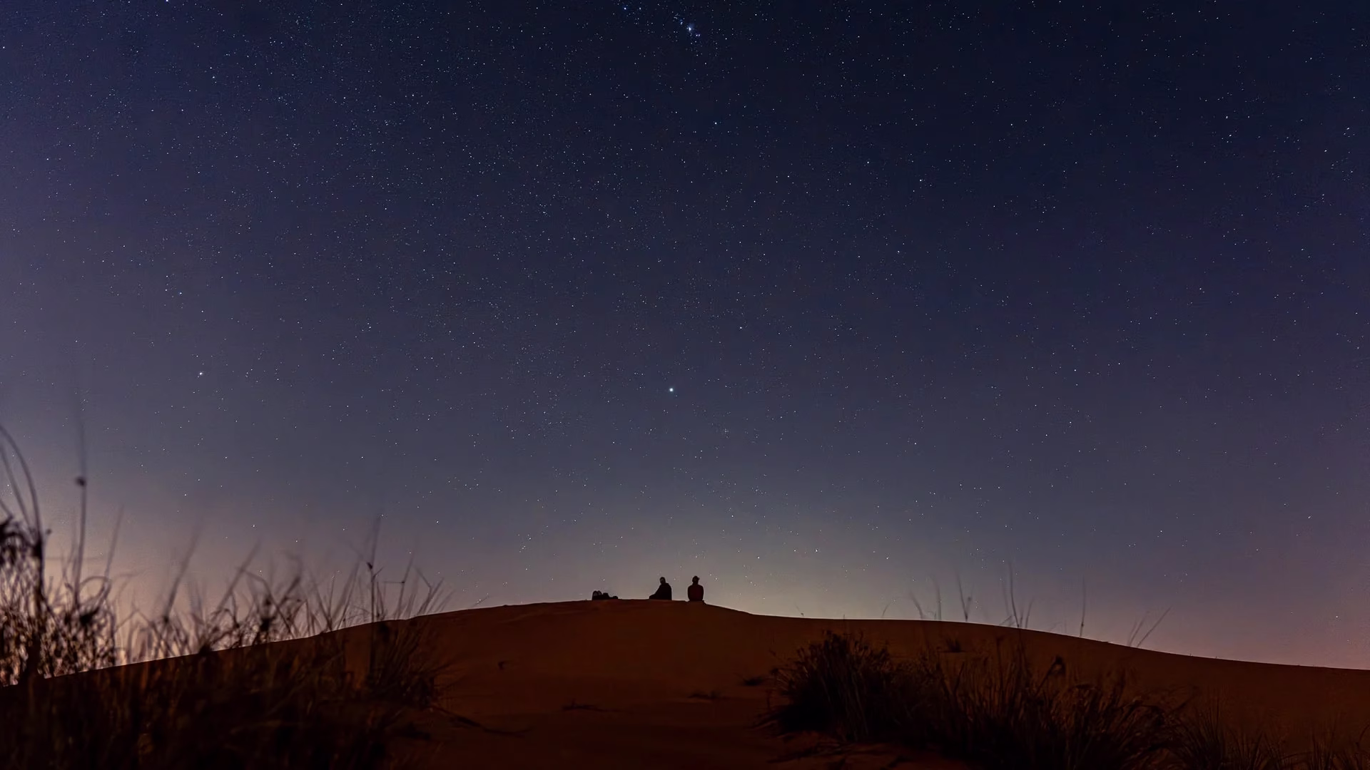 Tourists enjoying a night desert safari Dubai with sand dune bashing, camel trip, and BBQ dinner in the scenic Dubai desert.