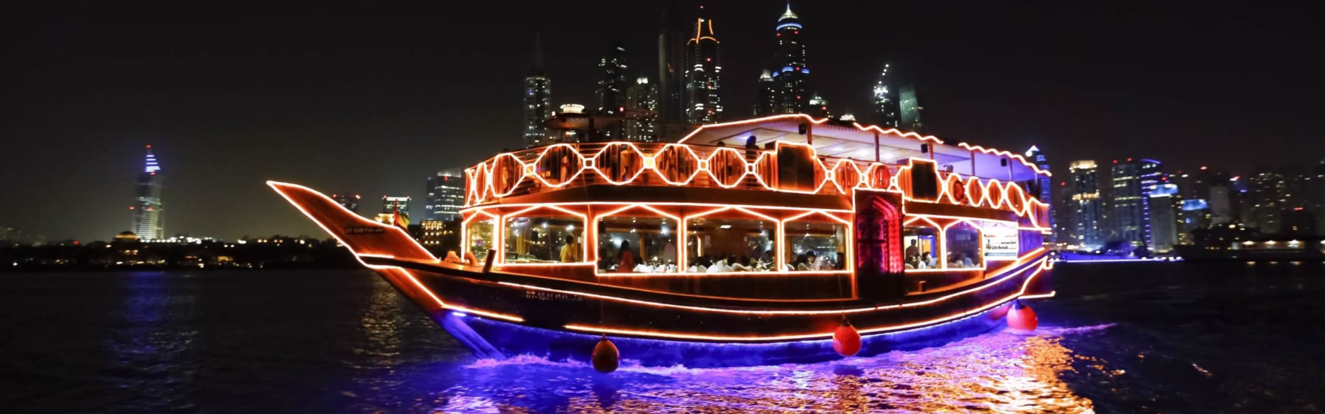 Traditional wooden boat sailing on the Dhow Creek during a scenic creek dhow cruise tour, with guests enjoying a relaxing dhow cruise dinner along the cruise creek.