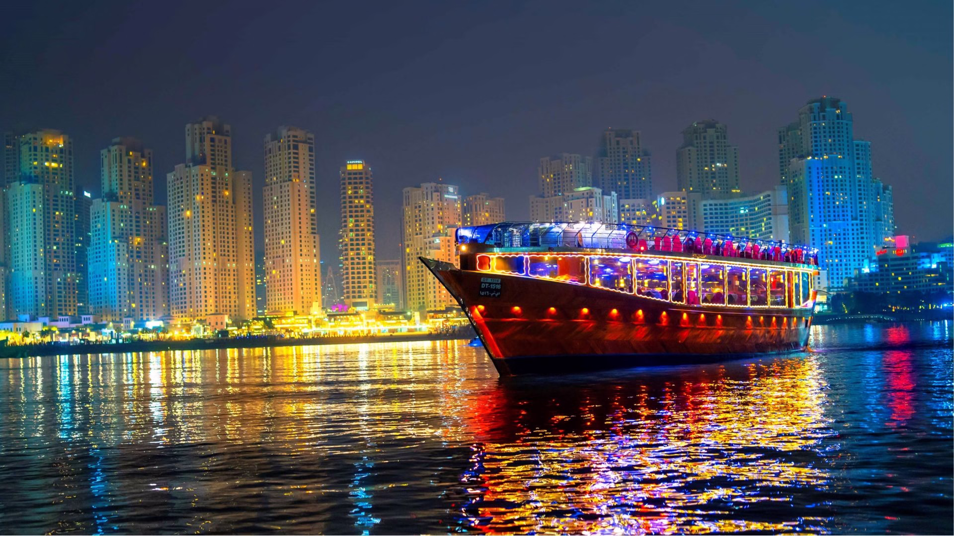 Guests enjoying a dinner cruise Dubai Marina on a traditional dhow with views of the illuminated skyline during a marina cruise Dubai.