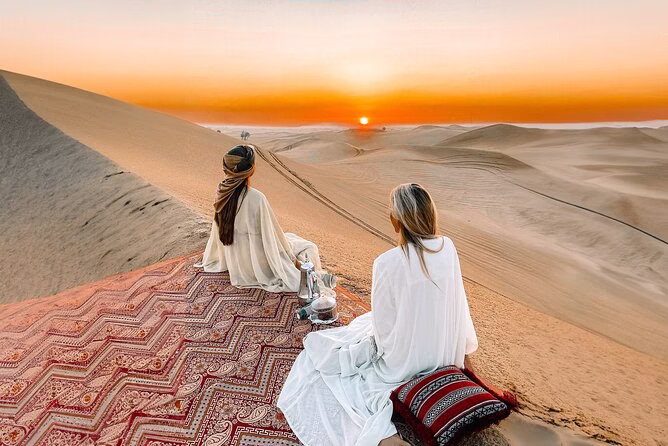 Tourists enjoying a sunrise desert safari Dubai at a scenic desert safari location with views of the golden sand dunes during early morning.