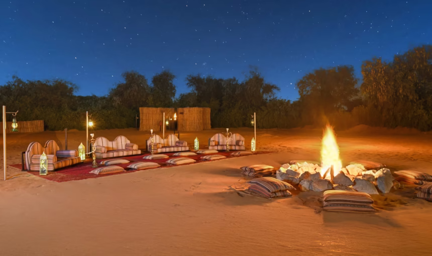 Tourists enjoying desert safari Dubai dune bashing in a 4x4 vehicle amid golden sand dunes with a scenic desert backdrop.