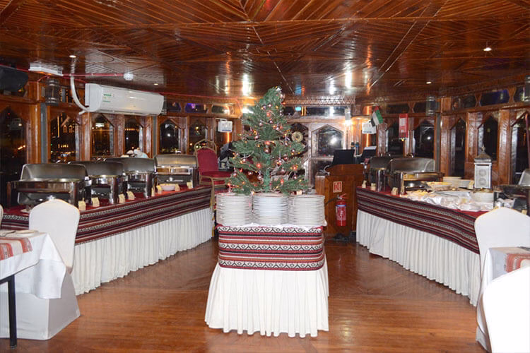 Traditional wooden boat sailing on the Dhow Creek during a scenic creek dhow cruise tour, with guests enjoying a relaxing dhow cruise dinner along the cruise creek.