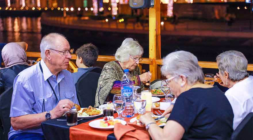 Traditional wooden dhow sailing on Dubai Creek during a dhow cruise in Dubai, offering a scenic Dubai Creek dhow cruise with buffet dinner experience.