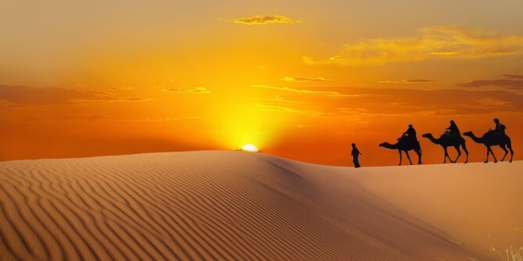 Tourists enjoying a sunrise desert safari Dubai at a scenic desert safari location with views of the golden sand dunes during early morning.