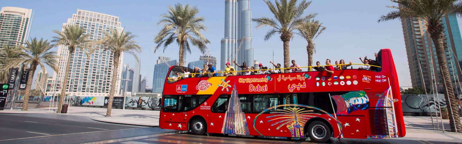 Red Bus Tour Dubai driving past famous Dubai landmarks, offering a city tour with hop on hop off sightseeing bus service.