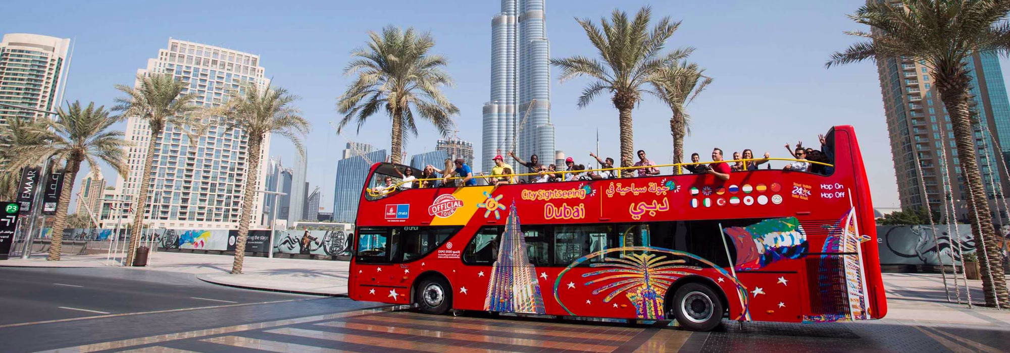 Dubai sightseeing bus driving past city landmarks on a hop-on hop-off red bus tour in Dubai.