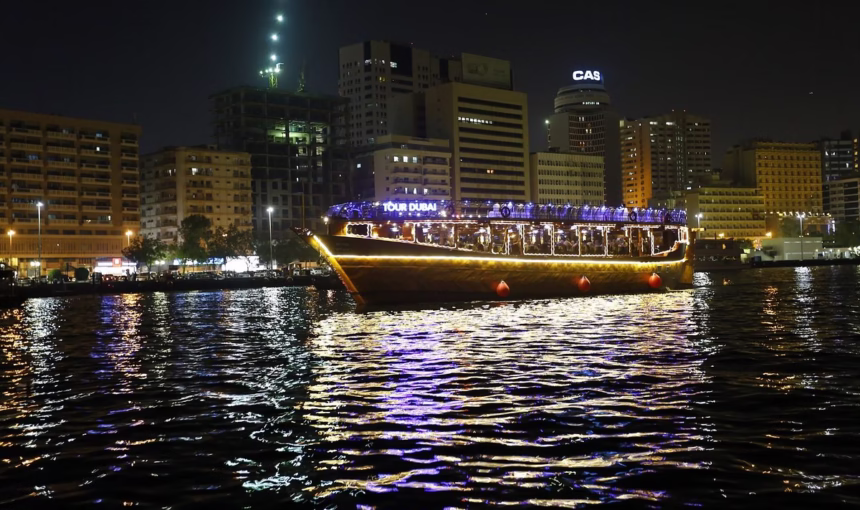 Dhow Cruise At Creek: Scenic Or Skippable? Honest Take › Forever Tourism LLC Traditional wooden boat sailing on Dubai Creek during a dhow cruise at Creek with dinner, lights, and guests enjoying the scenic Creek dinner cruise.