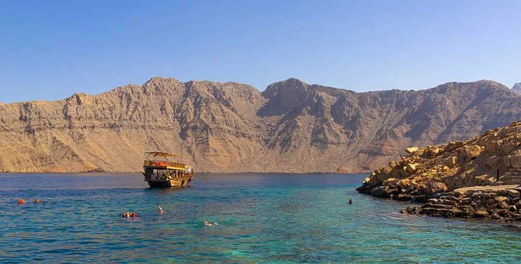 Dhow sailing through Dibba Musandam fjords under the sun – dibba musandam cruise deals