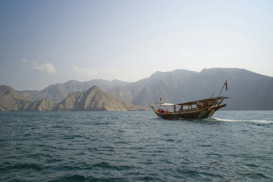 Traditional wooden dhow sailing through Musandam Dibba fjords on a Dhow Cruise Dibba Musandam
