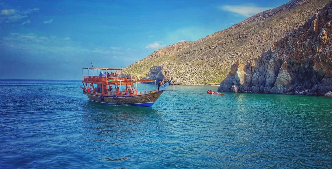 Traditional dhow sailing on crystal waters during a Musandam Dibba trip