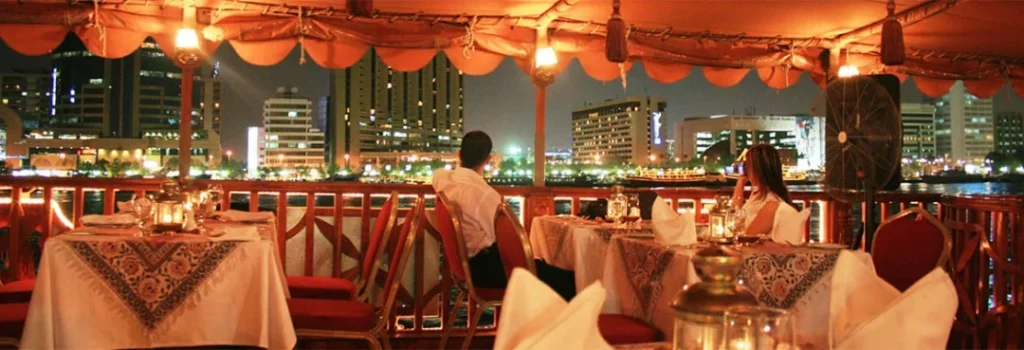 Couple enjoying a creek cruise dinner aboard a traditional dhow under Dubai’s night skyline