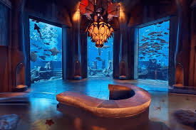Tourist walking through the glass tunnel with sharks and rays swimming above at Lost Chambers Aquarium — a must-see with lost chambers tickets