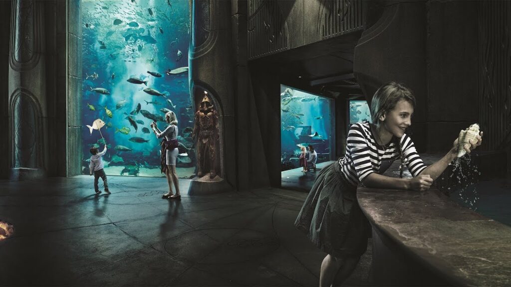 › Forever Tourism LLC Underwater tunnel at Lost Chambers Atlantis Aquarium with a variety of fish, sharks, rays visible through glass walls.