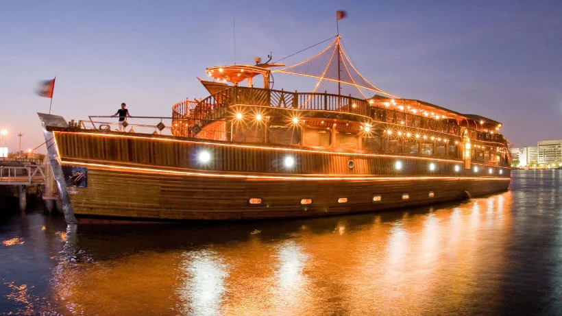Couple enjoying a creek cruise dinner aboard a traditional dhow under Dubai’s night skyline